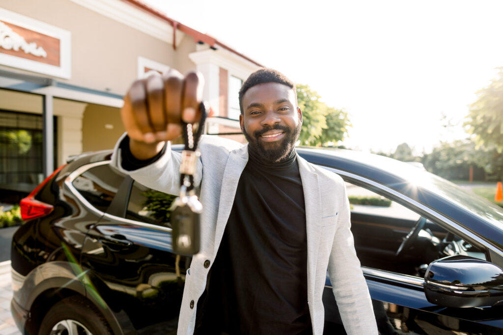 Portrait of an African-American man holding the keys to his new car.