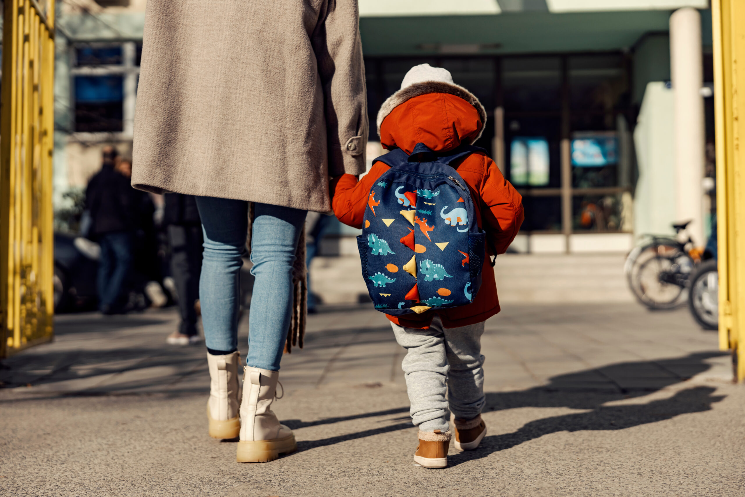 A mother entering the kindergarten yard with her preschooler boy